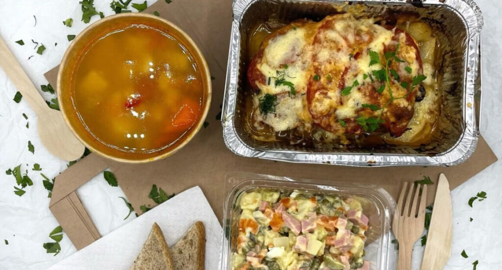 На столе тарелка супа, салат "Оливье" и мясное блюдо