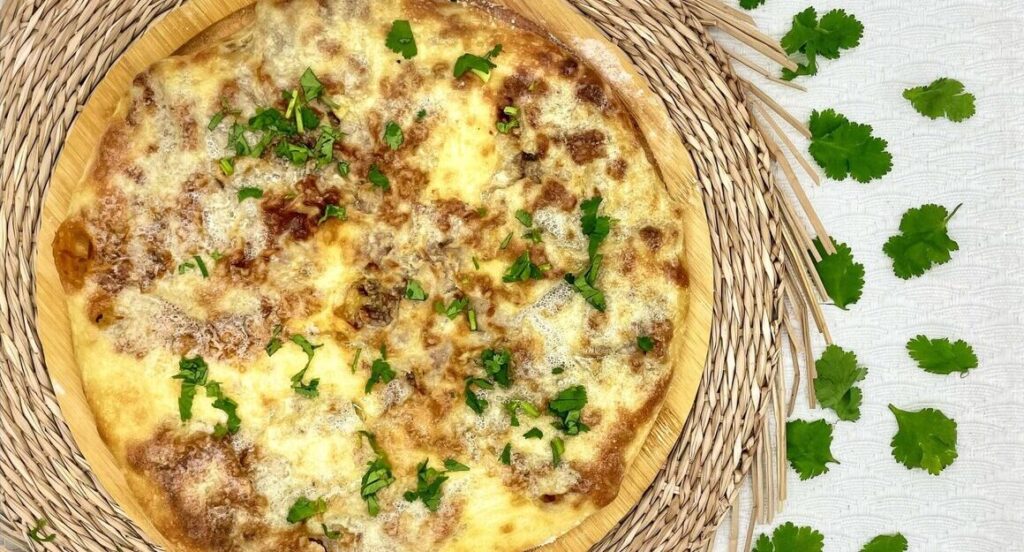 Осетинский пирог с мясом и кусочками зеленого лука на тарелке