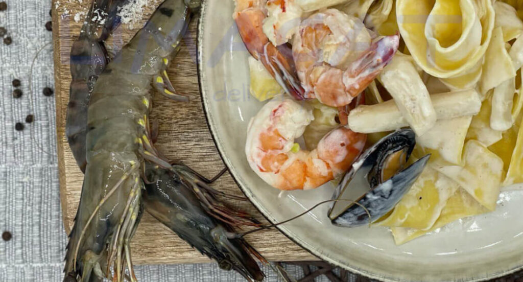 Паста с Морепродуктами на белой тарелке на деревянной доске, украшенной кальмарами